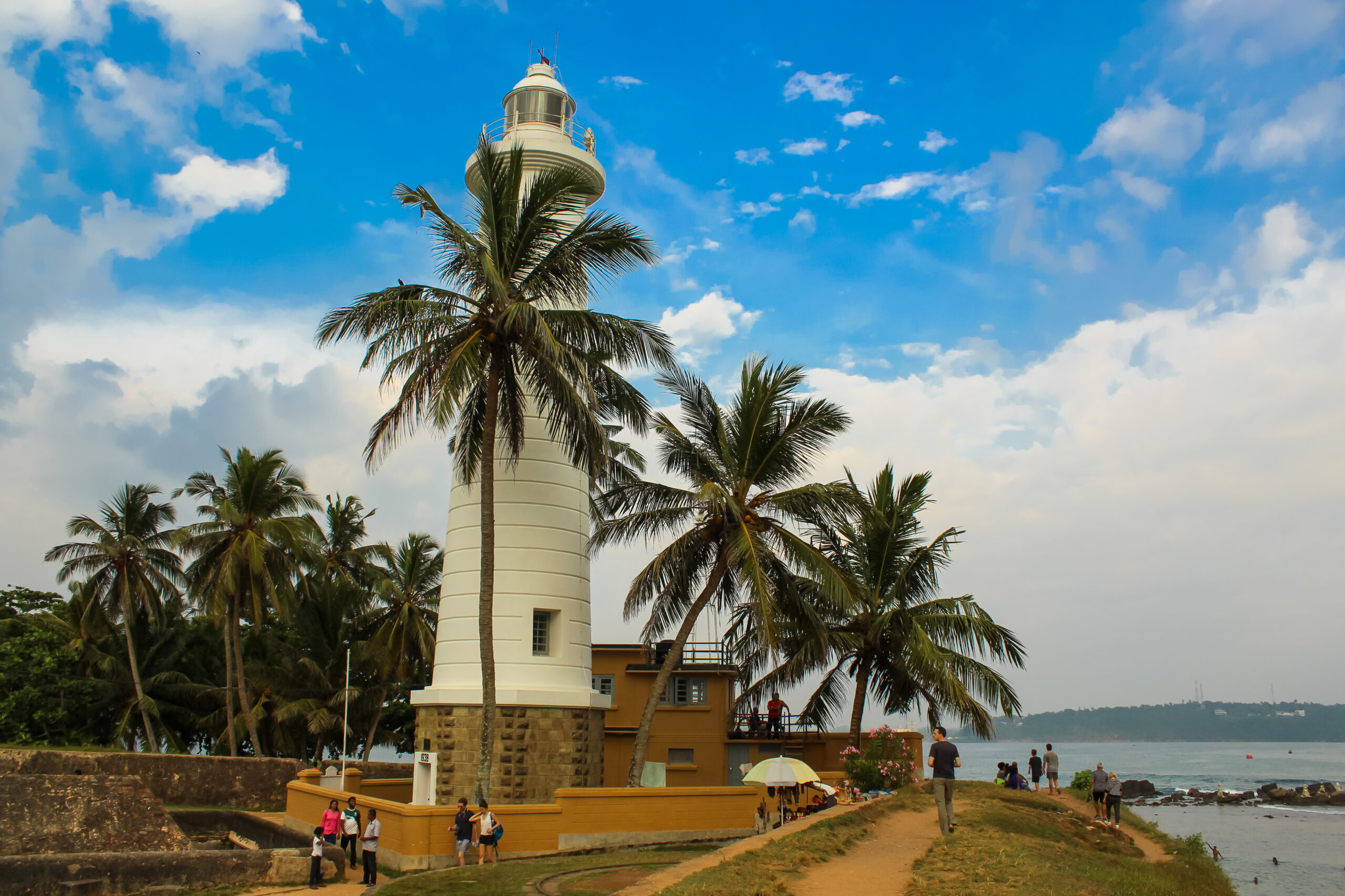 Lighthouse in Galle fort, Sri Lanka. Indian ocean shore, palms, blue cloudy sky. Sri Lanka.